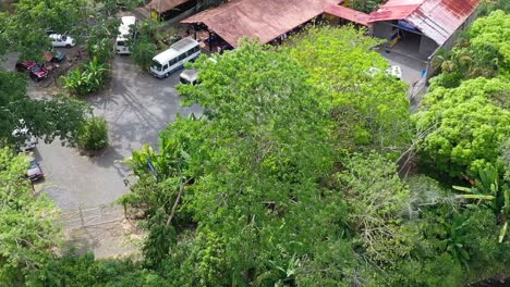 Rural-restaurant-with-transport-buses-and-people-eating,-Aerial-approach-shot