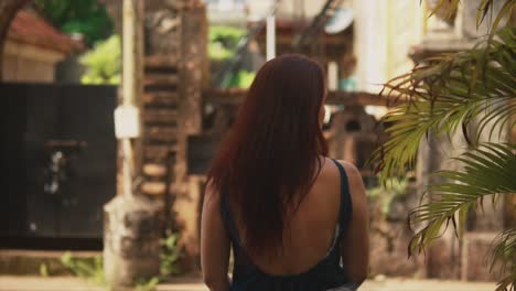 Brunette-Indian-woman's-back,-next-to-some-plants,-looking-at-the-historical-streets-of-Fontainhas,-India