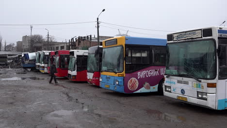 Un-Trabajador-Pasa-Junto-A-Los-Autobuses-Alineados-En-Un-Depósito-Con-Parabrisas-Destrozados,-Daños-Causados-Por-Un-Misil-Ruso-S-300-Que-Golpeó-El-Sitio-De-Infraestructura-Civil-En-Las-Primeras-Horas-De-La-Mañana