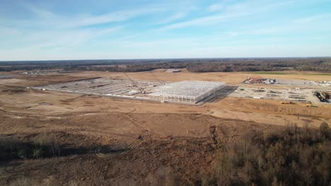 Aerial-slow-approach-of-steel-structure-under-construction-surrounded-by-heavy-machinery-and-cranes