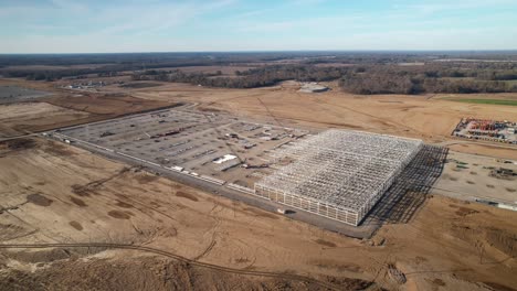 Aerial-slow-zoom-in-of-steel-structure-under-construction-surrounded-by-heavy-machinery-and-cranes