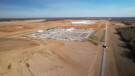 Acercamiento-Lento-Aéreo-De-Una-Gran-Estructura-De-Acero-En-Construcción-Rodeada-De-Grúas,-Equipo-De-Construcción-Y-Tierra-Graduada