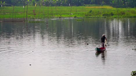 Slow-motion-shot-of-fisherman-with-traditional-hut-in-boat-throwing-net-into-lake