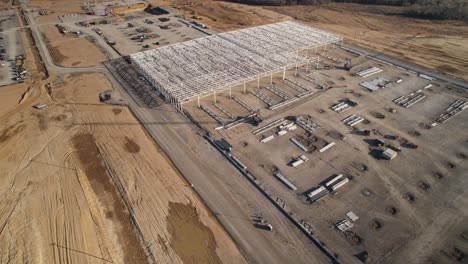 Aerial-approach-and-zoom-in-of-steel-structure-under-construction-surrounded-by-heavy-machinery-and-cranes