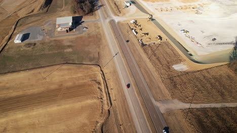 Aerial-reveal-of-sprawling-new-construction-following-cars-travelling-on-adjacent-highway