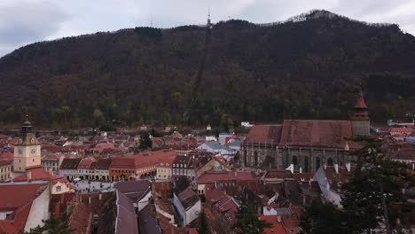 Toma-Completa,-Vista-Escénica-De-Techos-Y-Casas-En-Brasov,-Rumania,-Rango-Forestal-En-El-Fondo