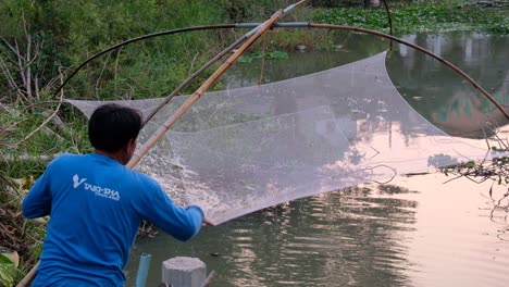 Fischer-Schüttelt-Wasser-Aus-Einem-Aufgehängten-Garnelennetz