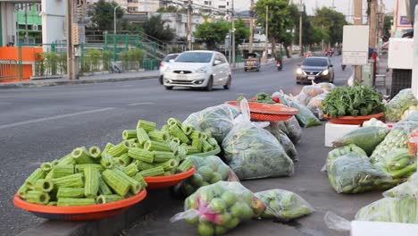 Traffic-Passes-By-Fresh-Vegetable-Stall-On-Roadside,-LOCKED-DOWN-SHOT