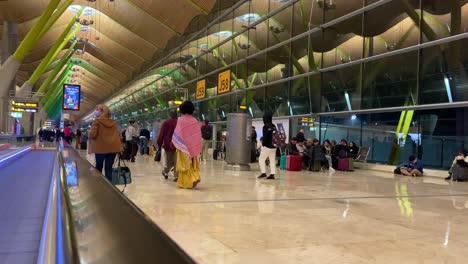 Gente-Caminando-Hacia-Su-Puerta-Mientras-Otros-Esperan-Su-Vuelo-En-El-Aeropuerto-De-Barajas,-Madrid