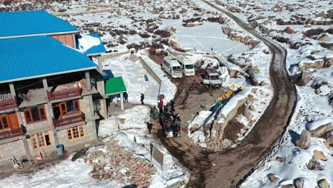 Toma-Aérea-De-Un-Grupo-De-Viajeros-Bajando-El-Ritmo-En-Medio-Del-Nevado-Paisaje-Invernal-De-Spiti