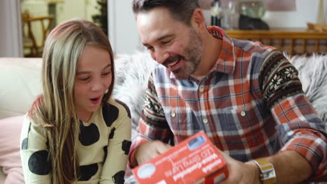 El-Padre-Abre-El-Regalo-De-Navidad-De-Su-Hija-Mientras-Le-Sonríe