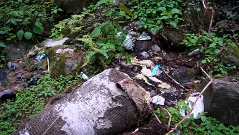 Basura-Esparcida-En-El-Suelo-Rocoso-Del-Bosque-En-La-Montaña-En-Manali,-Himachal-Pradesh,-India---Inclinación-Hacia-Abajo,-Tiro-Panorámico