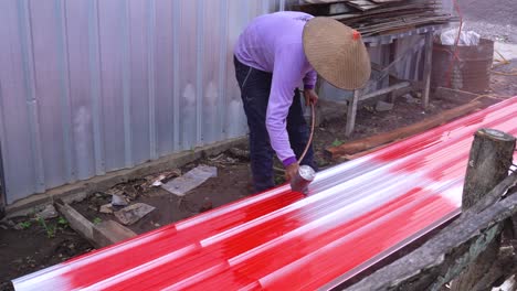 Trabajador-Asiático-Usando-Una-Pistola-Rociadora-Para-Pintar-Una-Hoja-De-Metal-Del-Techo