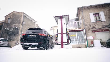 Coche-En-Una-Pequeña-Gasolinera-En-Invierno-Con-Nieve-Durante-El-Repostaje-De-Gasolina