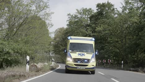 Vista-Frontal-De-La-Conducción-De-Ambulancia-En-El-Camino-Del-Bosque,-Tiro-De-Muñeca-En-Cámara-Lenta