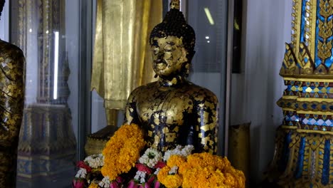 Las-Flores-Rodean-La-Figura-De-Buda-En-Un-Templo,-Se-Inclinan-Hacia-Arriba