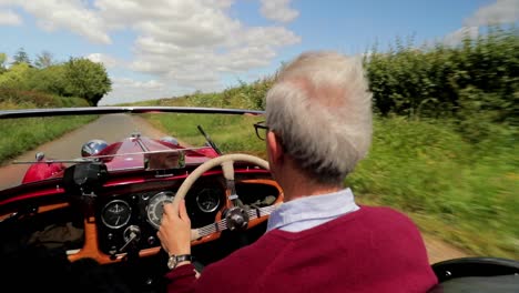 Red-1939-Morgan-4-4-'Le-Mans'---60s-gent-from-behind-driving---4K--open-top-sports-car-in-English-countryside-on-a-picture-perfect-day