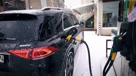 Car-on-gas-station-with-nozzle-in-tank-is-refueling-gasoline-in-winter