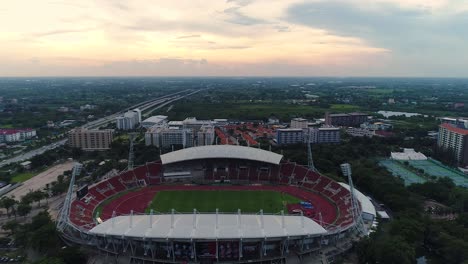 Vista-De-Pájaro-Del-Estadio-Principal-De-La-Universidad-De-Thammasat-Con-Un-Dron-Viendo-El-Cielo-Con-Puesta-De-Sol,-Tailandia