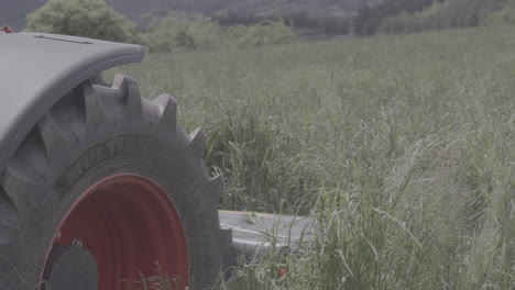 Tractor-mower-harvesting-grass-on-alpine-meadow-close-up