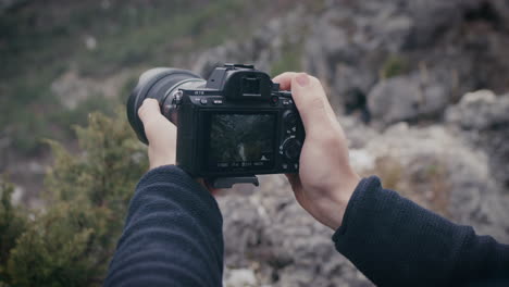 Cierre-Las-Manos-Sosteniendo-Una-Cámara-Sony-A-7iii-Mientras-Toma-Una-Foto-Del-Paisaje