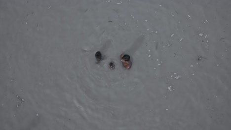 Two-Indian-Men-Taking-Dip-In-The-Bathing-Ghats-At-Ram-Ki-Paidi,-Ayodhya,-Uttar-Pradesh,-India---High-Angle-Shot