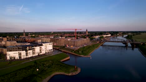 Aerial-approach-passing-Kade-Noord-apartment-complex-at-the-riverbank-of-river-IJssel-towards-Kade-Zuid-construction-site-develop-area-in-Noorderhaven-Zutphen-neighbourhood