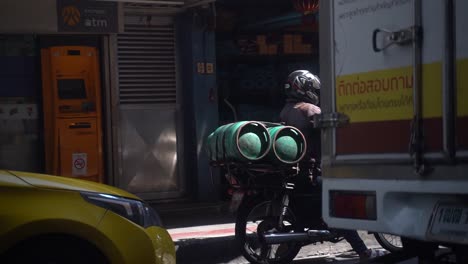 Slow-motion-shot-of-a-man-on-a-motorbike-carrying-two-gas-cylinders-in-the-traffic