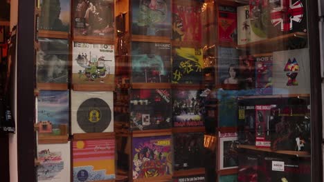 Close-up-panning-shot-of-a-vintage-record-store-window-displaying-vinyl-records-in-Brussels,-Belgium