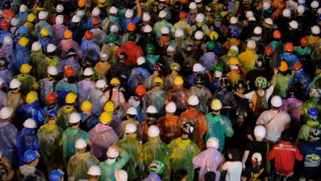 Cientos-De-Manifestantes-Equipados-Con-Impermeables-Y-Cascos-De-Seguridad-Marchando-Por-La-Carretera-Demostrando-Protestas-Contra-El-Gobierno-De-Tailandia-Por-La-Noche