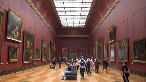 Tiro-Inclinado-Dentro-De-Una-Habitación-Con-Pintura-Ubicada-En-El-Museo-Del-Louvre,-Visitantes-Con-Máscaras-Mirando-Alrededor