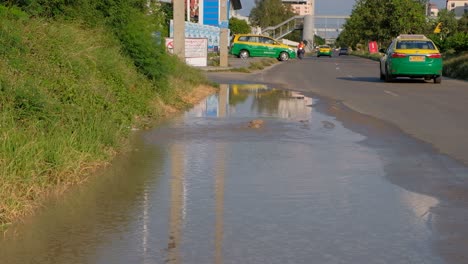 Man-Driving-Motorcycle-Driving-On-Road-With-Flood-Due-To-Underground-Broken-Pipe-In-Thailand