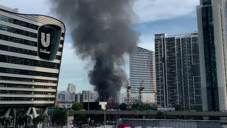 Edificio-En-Llamas-Con-Humo-Negro-Que-Se-Eleva-Cerca-De-Unilever-A-Lo-Largo-De-Rama-Ix-Road,-Huai-Khwang,-Bangkok,-Tailandia---Plano-General