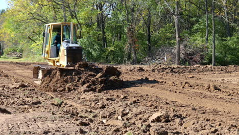 John-Deere-560H-LGP-bulldozer-leveling-dirt-at-construction-site-in-rural-Illinois-in-early-autumn-with-a-dump-truck-in-background