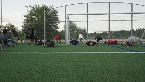 Hombres-Haciendo-Ejercicio-Y-Burpies-En-Un-Campo-De-Fútbol-Por-La-Mañana