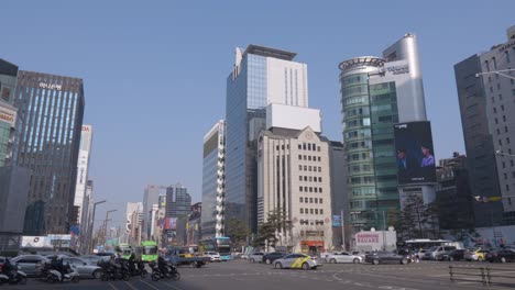 Tráfico-De-Cruce-Gangnam-daero-Con-Vistas-A-La-Torre-De-Cristal,-Torre-Iz,-Torre-Medi-En-El-Centro-De-Seúl-En-Un-Día-Soleado