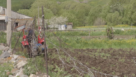 Hombre-Trabajando-En-El-Campo-Conduciendo-Un-Tractor-Arando-Suelo-Agrícola-En-Moliti,-Georgia