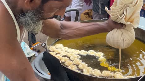 Street-vendor-cooking-sweet-snacks-Jalebi-outdoors-In-Iftar-Street-Market,-Dhaka,-Bangladesh