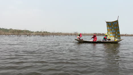 Aldeanos-Viajando-En-Un-Bote-A-Través-Del-Lago-Nokoue-En-Ganvie,-Benin,-áfrica-Occidental