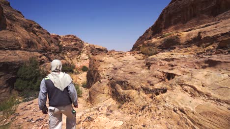 Local-arab-tourist-guide-walking-in-canyon-in-Petra-desert,-Jordan