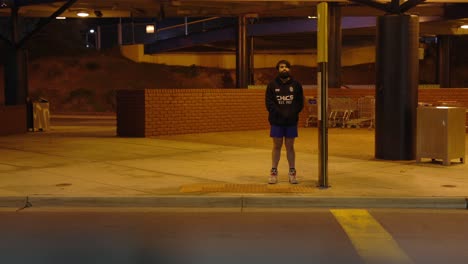 Man-waiting-at-bus-stop-dark-dingy-interchange-bad-lighting