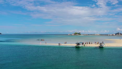 boats-on-tropical-sandbar-island-with-tourists-in-Belitung-Indonesia,-aerial