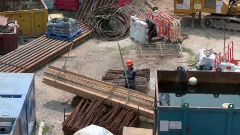 Un-Trabajador-De-Ingeniería-Chino-Coloca-Una-Pila-De-Tableros-De-Madera-Mientras-Una-Grúa-Los-Levanta-En-Un-Proyecto-De-Construcción-En-Desarrollo-En-Hong-Kong