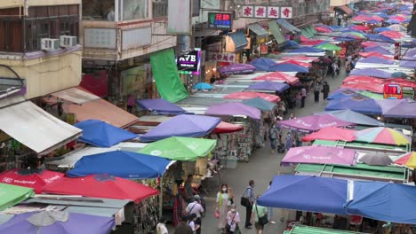 Eine-Hochsichtaufnahme-Von-Käufern,-Die-Durch-Die-Marktstände-Der-Fa-Yuen-Street-Gehen,-An-Denen-Gemüse,-Obst,-Geschenke-Und-Modewaren-In-Hongkong-Verkauft-Werden