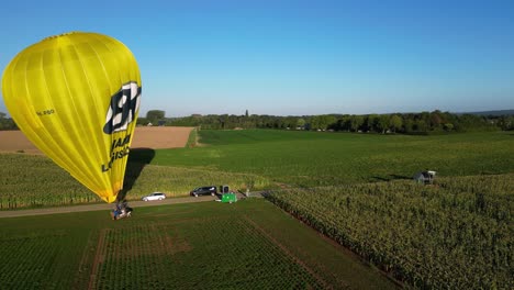 Vista-Aérea-Matutina-Del-Globo-Aerostático-Amarillo-Brillante-Que-Se-Está-Preparando-Para-El-Vuelo-En-El-Campo-En-Los-Países-Bajos