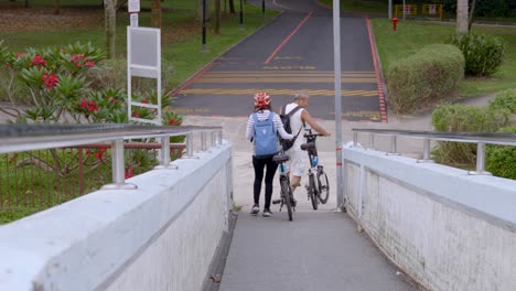 Cyclists-Pushing-Their-Bicycles-Across-The-Changi-Point-Bridge-To-Changi-Beach-In-Singapore