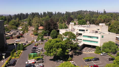 Centro-Comercial-Eugene-Y-Edificios-De-Oficinas,-Dron-Descendiendo-Sobre-El-Estacionamiento