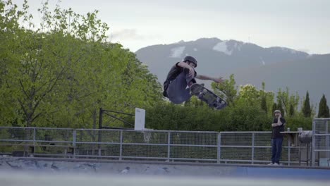 Male-Skater-in-Skatepark-Ollies-with-Board-in-Half-Pipe,-Slow-Motion