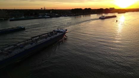 Aerial-View-Of-Maxima-Inland-Liquid-Tanker-Sailing-Along-Oude-Maas-During-Bright-Orange-Yellow-Sunset-Skies