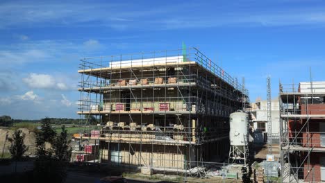 Langsame-Kumuluswolken-Bilden-Sich-Im-Zeitraffer-Hinter-Baustelle-Mit-Außenfassade-In-Sonnenlicht-Und-Schatten-Und-Hochhauswolke-In-Gegenrichtung